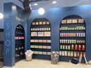 Messestand Shop mit Empfangstheke Streifen, beleuchtetem Shopregal, Hockern, Tischen, Regalen